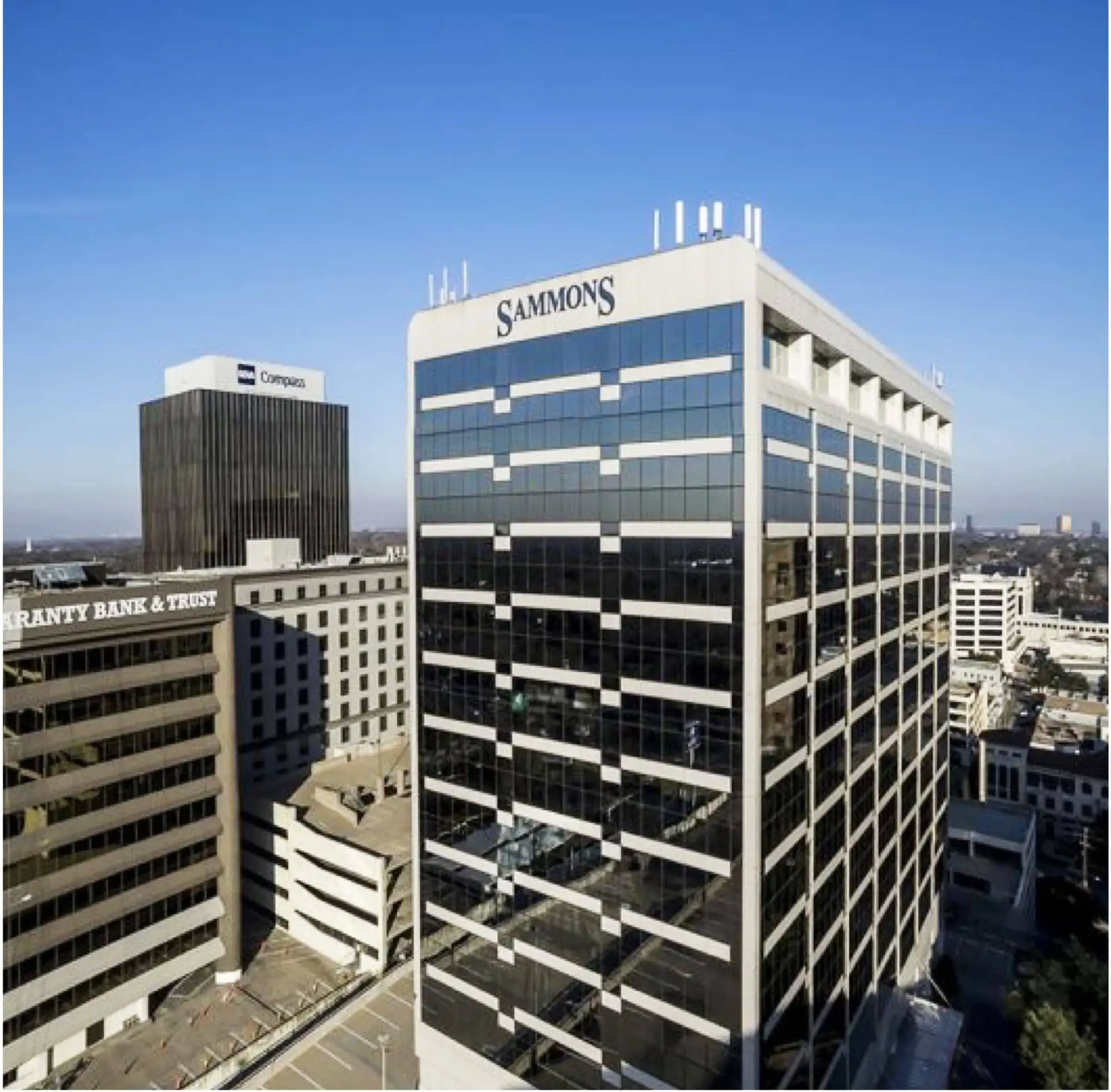 Skyline of tall glass office buildings with Sammons sign on the facade.
