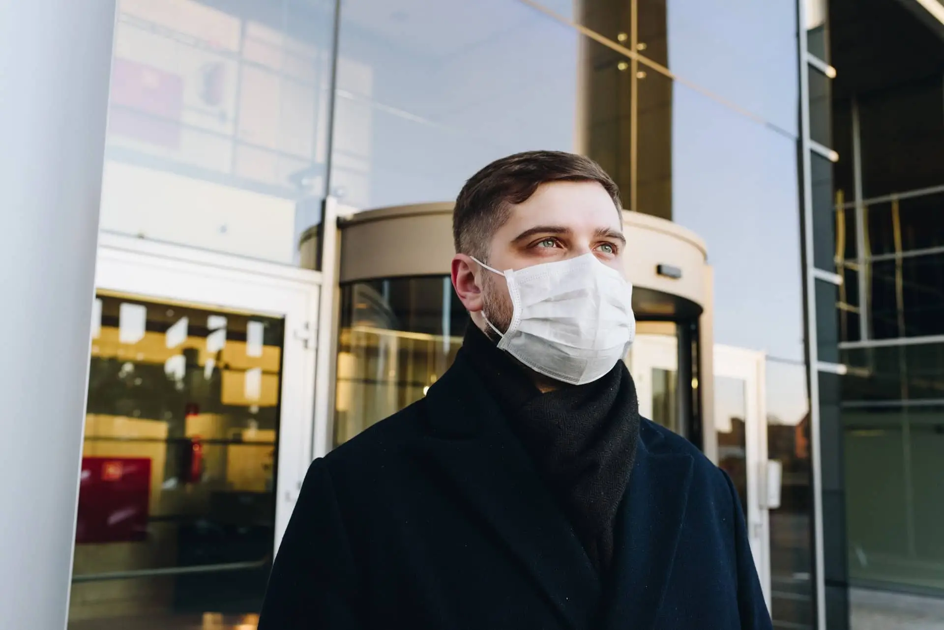 A man stands outside work office with a mask on amid COVID-19
