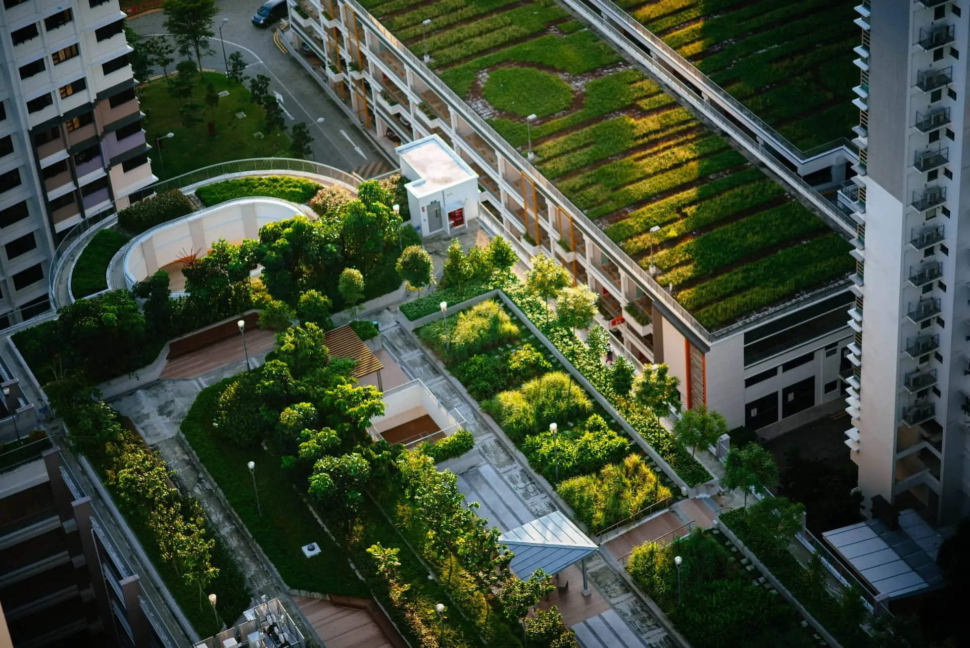 Aerial view of a green-roofed residential complex with terraces and walkways between high-rise buildings.