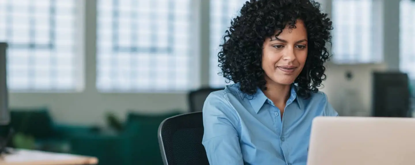 Woman uses laptop; modern office.