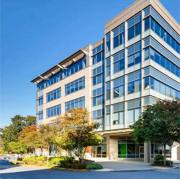 Modern office building stands amidst landscaping on a sunny day.