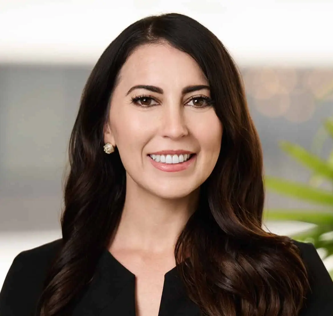 Smiling professional headshot of a woman with long dark hair in a black blazer.