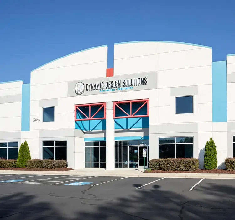 Front facade of a modern office building with Dynamic Design Solutions sign, blue accents, and red window frames.