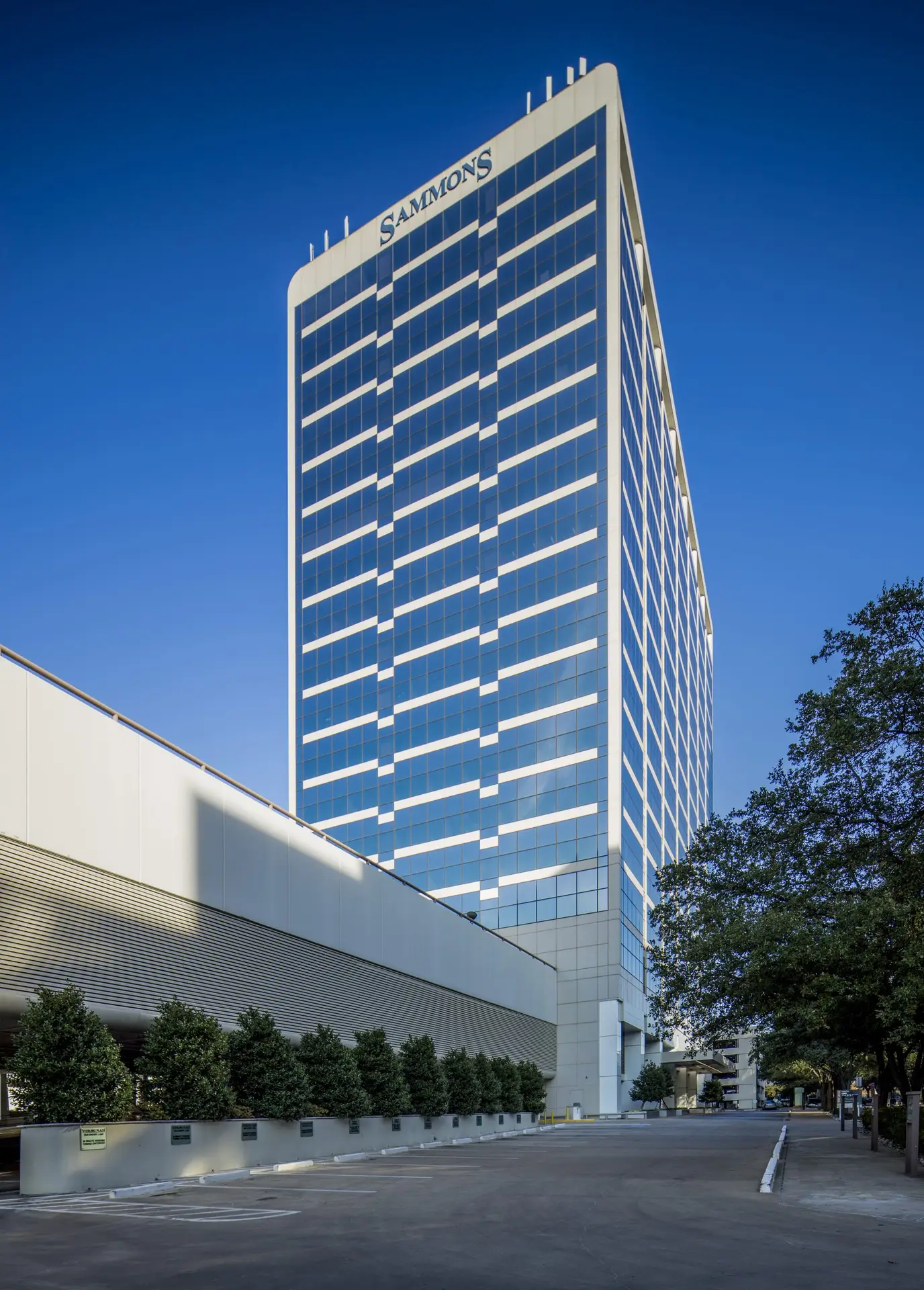 Sammons office tower with blue glass facade against a clear sky