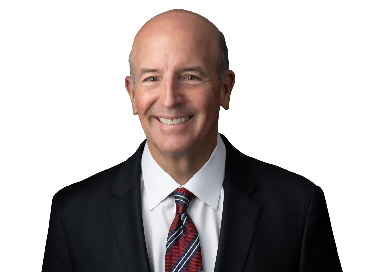 Smiling bald man in a dark suit, white shirt, and striped tie against a black background.
