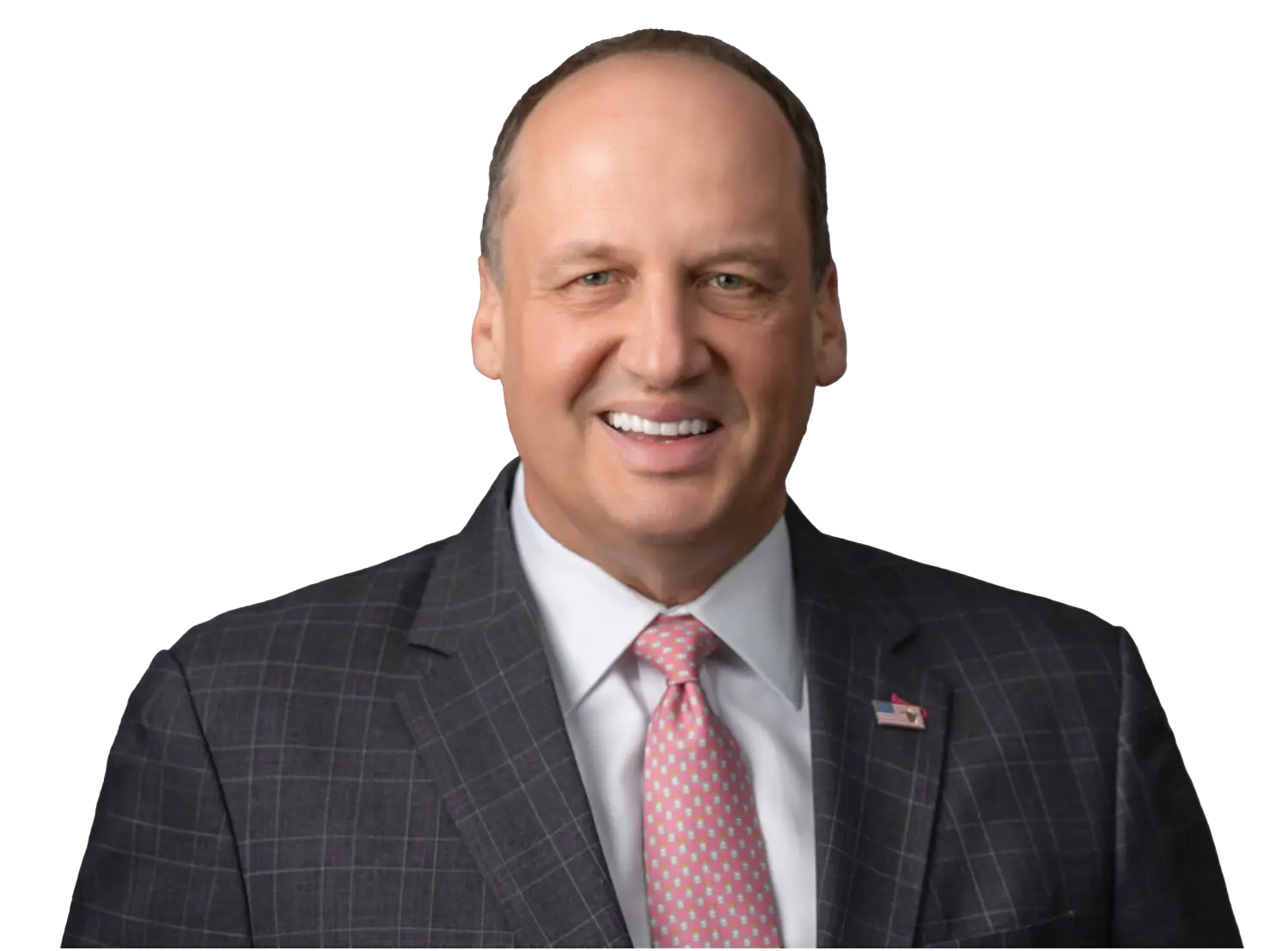 Smiling man in a dark plaid suit with a pink tie and American flag lapel pin.