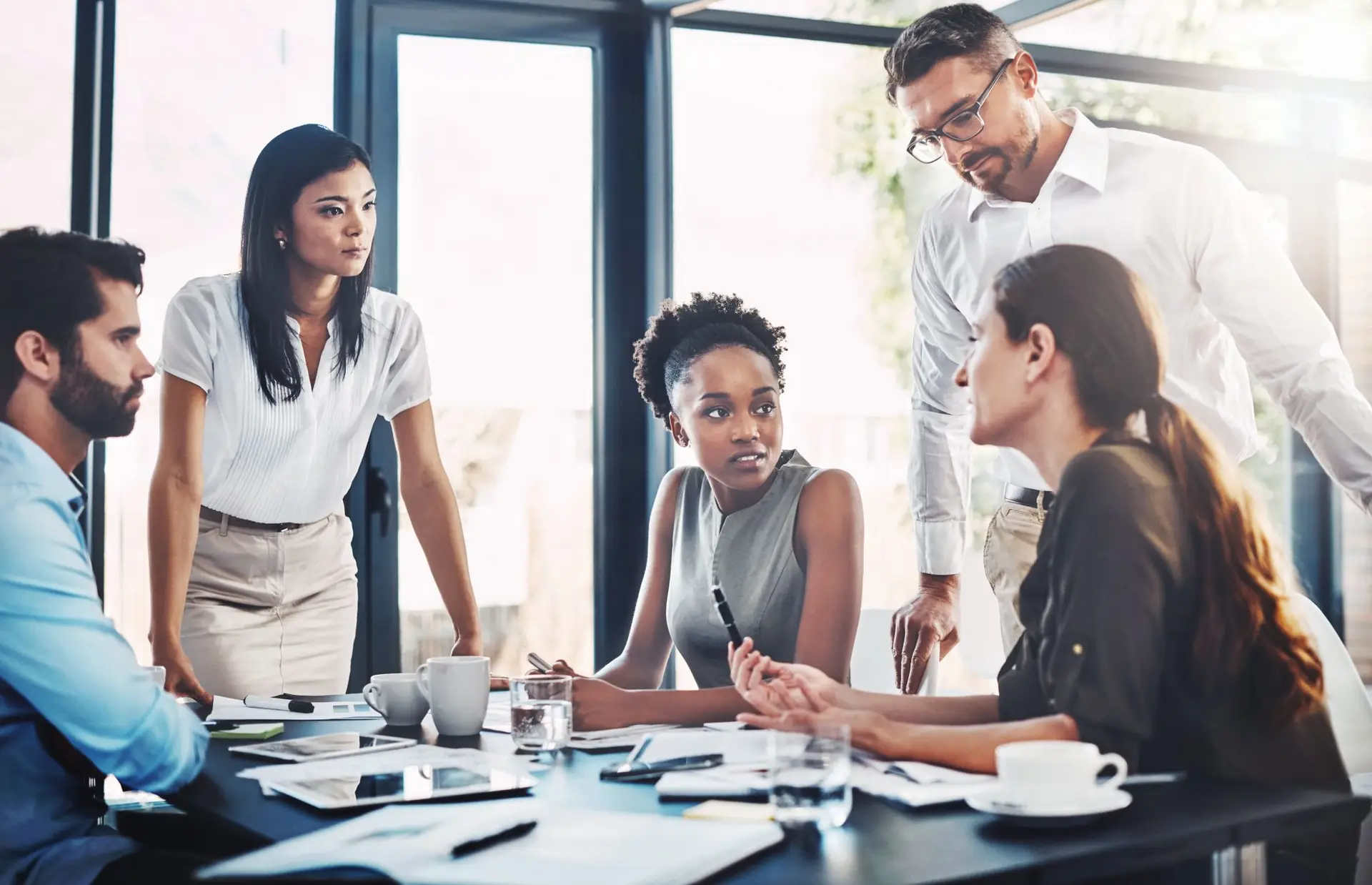 Businesspeople collaborate, discussing documents around a table in a modern office.